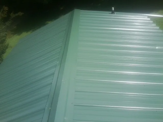 New green metal panels meeting at the ridge of a roof — Flat Roof Repair work by our crew in Bailey