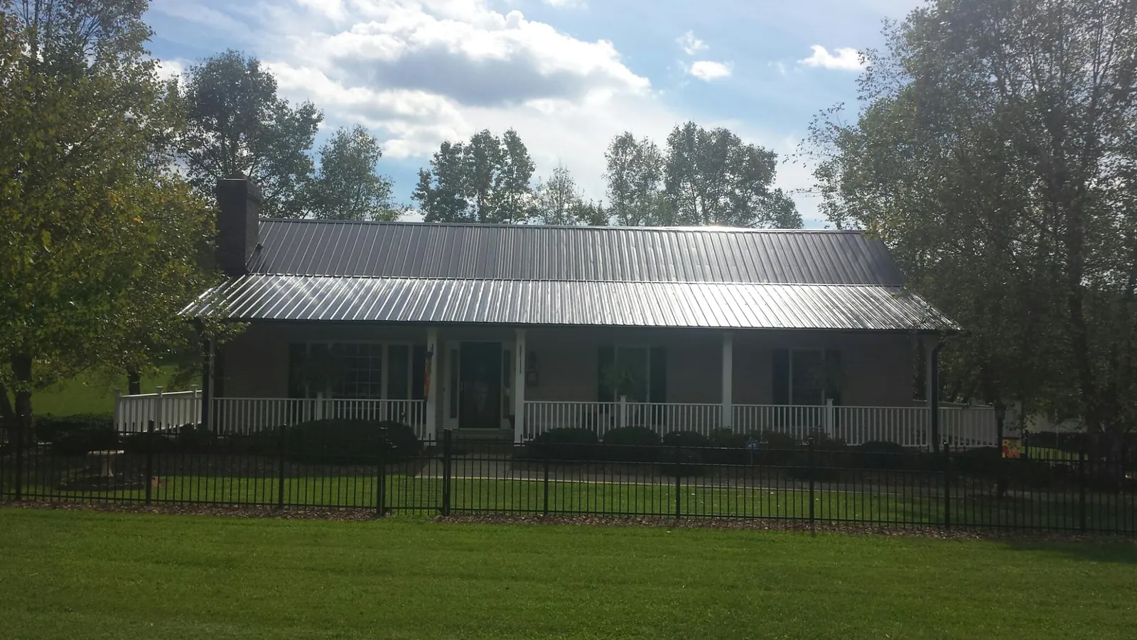 Gray metal roof on a brick ranch with a full width front porch — Gutter Guard Installation work by our crew in Bailey